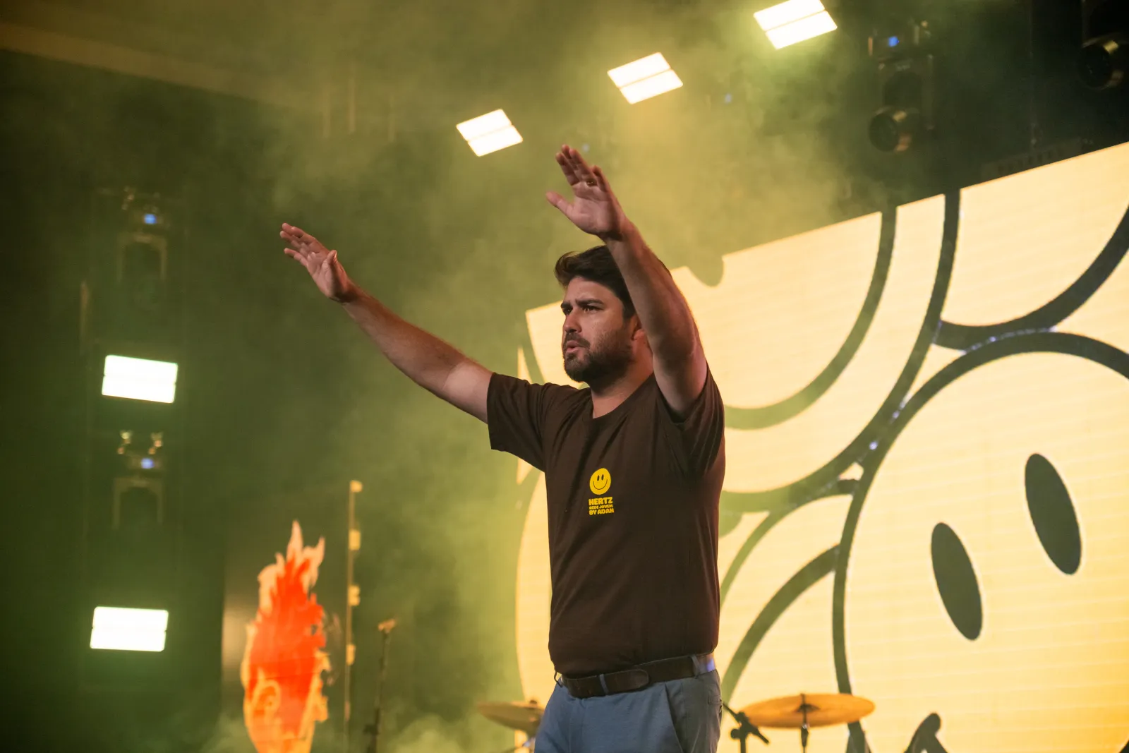 Líder adorando com os braços erguidos no palco da Conferência Hertz