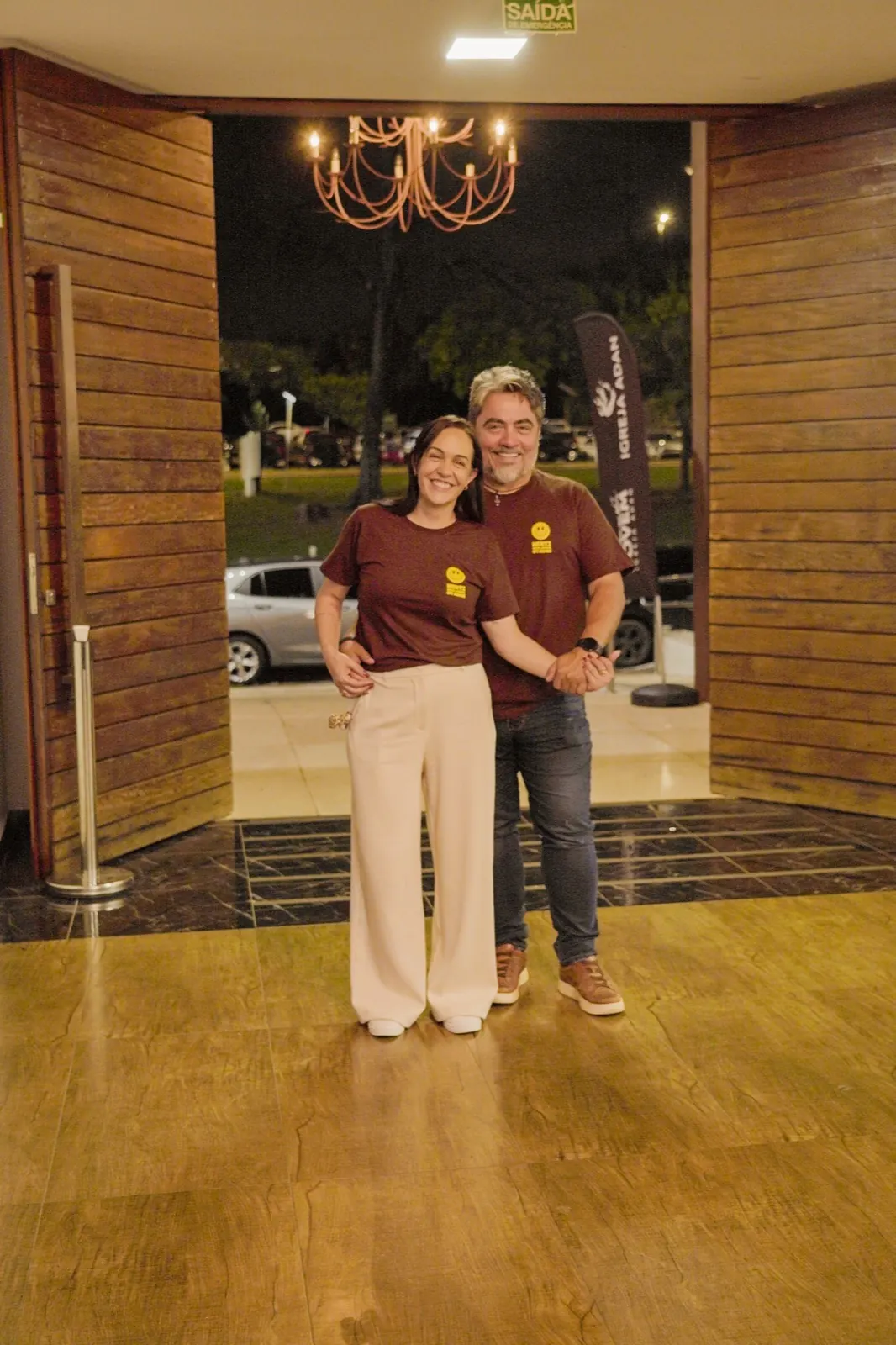 Casal sorrindo na entrada do auditório